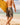 Man holding yellow surfboard in reef camo boardshorts walking into the ocean 