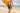 Man holding yellow surfboard in reef camo boardshorts walking into the ocean 
