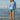 Woman on rocks wearing boardshorts and heather blue long sleeve sun shirt 