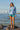 Woman on rocks wearing boardshorts and heather blue long sleeve sun shirt 